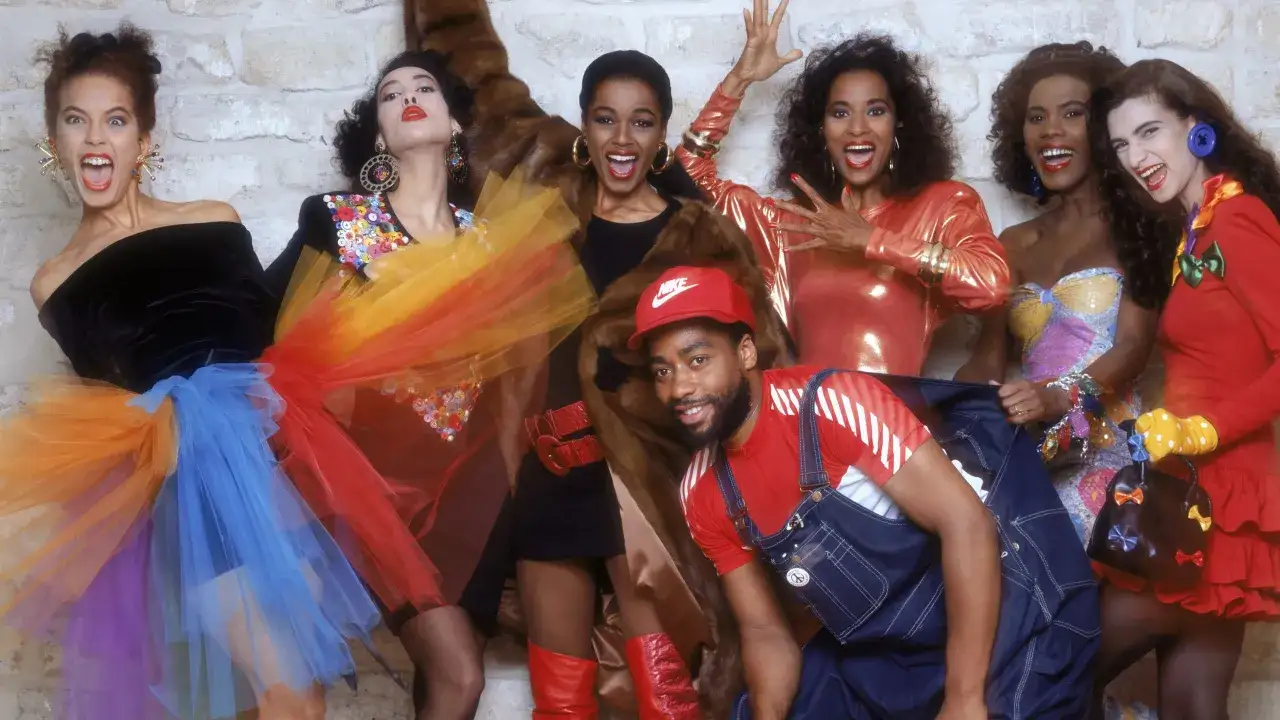Un gruppo di persone posa con abiti colorati e audaci, un'esplosione di moda anni 80.