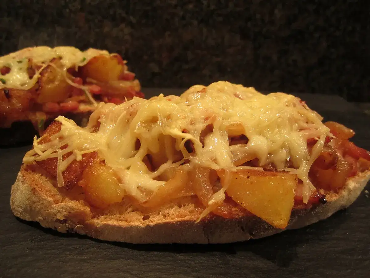 Tartines garnies de pommes de terre et lardons, recouvertes d'une g&eacute;n&eacute;reuse croute de fromage fondue. Un d&eacute;lice croustillant.
