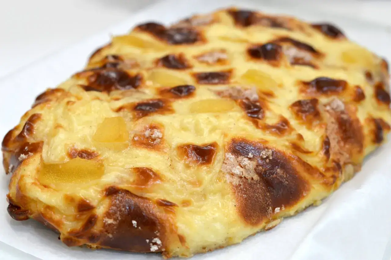 Deliciosa coca de San Juan con trozos de fruta y un dorado perfecto.