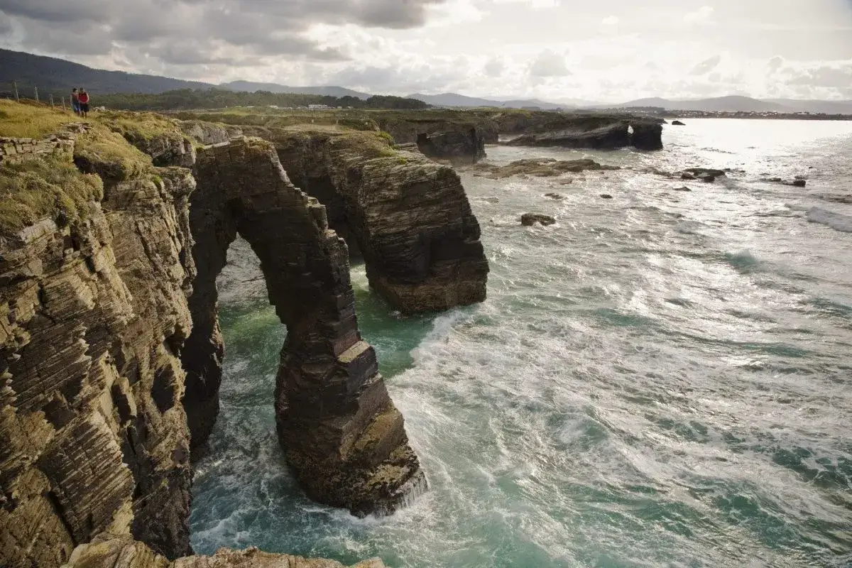 Acantilados y arcos naturales en la Playa de las Catedrales, Galicia. El mar rompe con fuerza contra las rocas.
