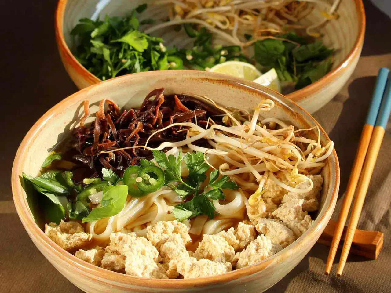 Eine Schüssel mit Pho, einer vietnamesischen Nudelsuppe, gefüllt mit Reisnudeln, Tofu, Sprossen, Kräutern und Jalapeños.