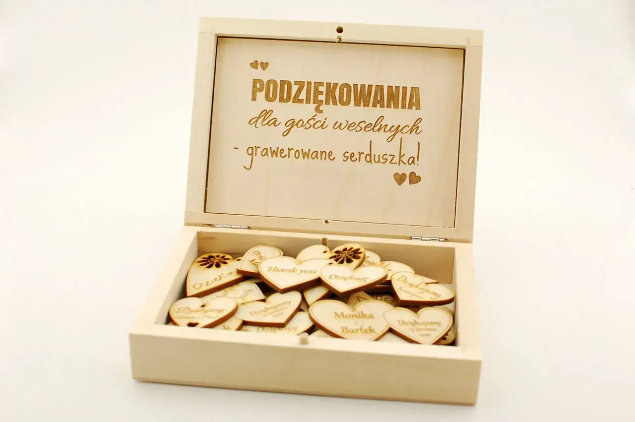 Drewniana skrzynka z wygrawerowanymi serduszkami, pełna wyrazów wdzięczności dla gości weselnych.
