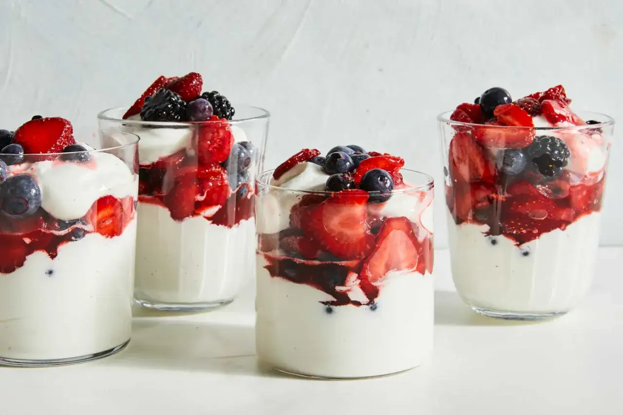 Vier Gläser mit cremigem Joghurt und frischen Beeren, ein köstlicher protein nachtisch.