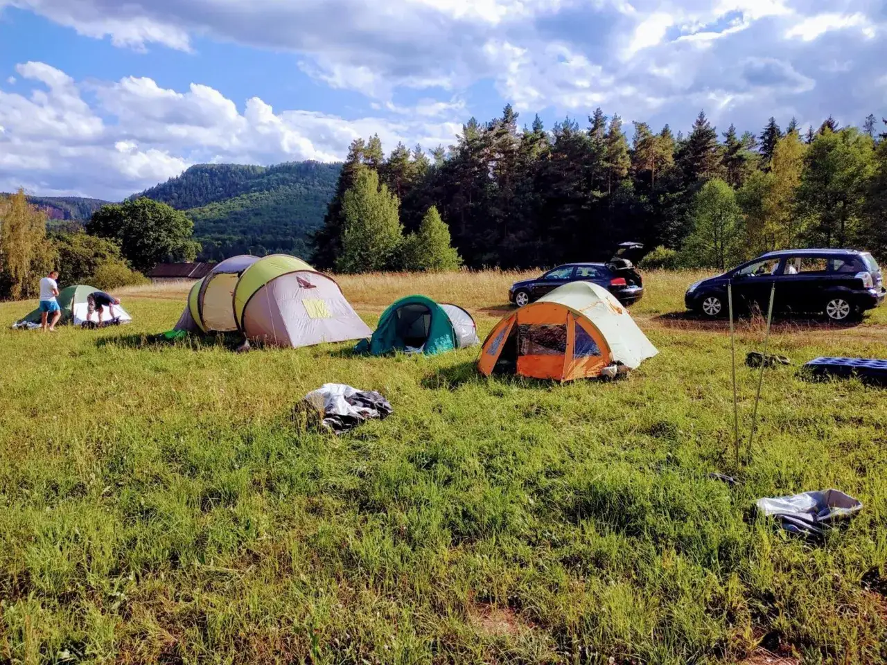 Namiotowe miasteczko na polanie, idealne na camping w Górach Stołowych. Dwa samochody gotowe do dalszej podróży.