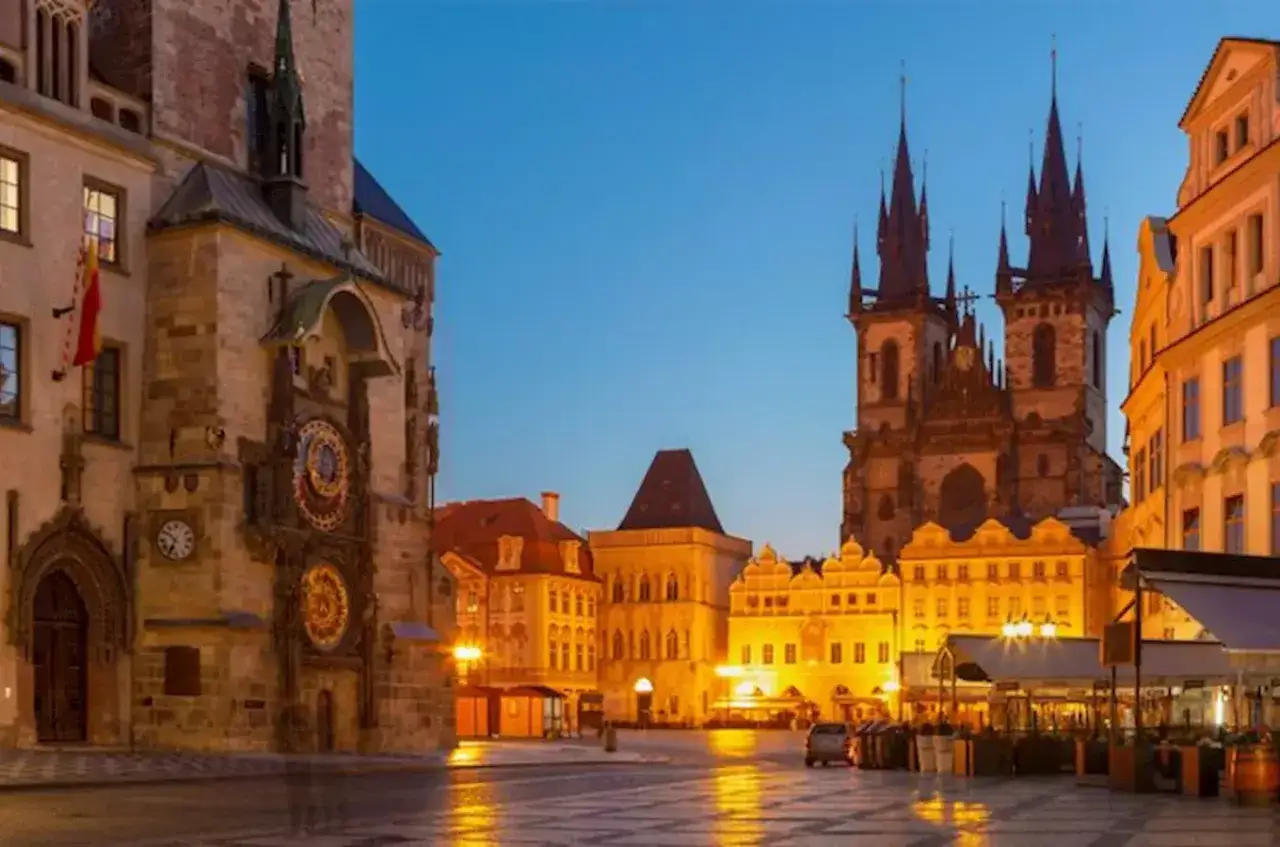 Wieczorny widok na stary rynek w Pradze. Widoczny zegar ratuszowy i kościół Marii Panny przed Tynem.