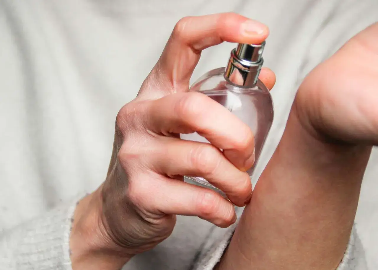 Dłoń z atomizerem perfum aplikuje zapach na nadgarstek. Wiesz, gdzie psikac perfumami, by pachnieć przez cały dzień.