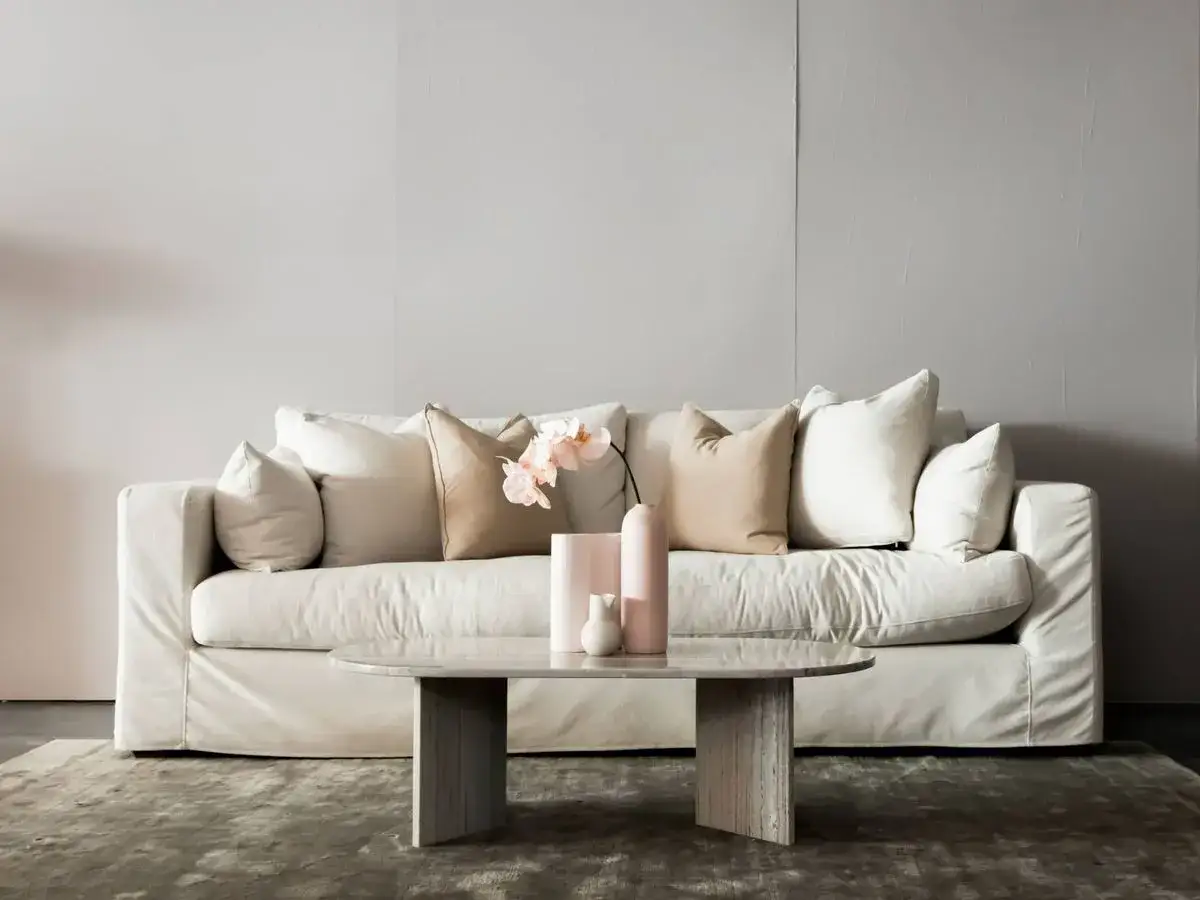 Sof&aacute; blanco con cojines en tonos neutros, una forma elegante de como colocar cojines en sof&aacute; para un look acogedor.