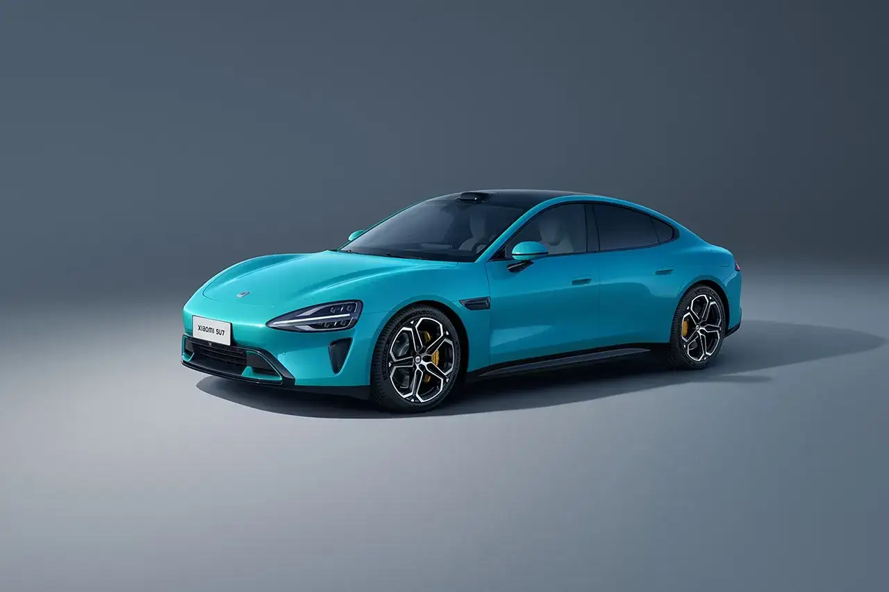 La **Xiaomi voiture** SU7, d'un bleu turquoise éclatant, se présente avec élégance sur un fond gris. Ses lignes modernes et son toit noir contrastent avec sa carrosserie.