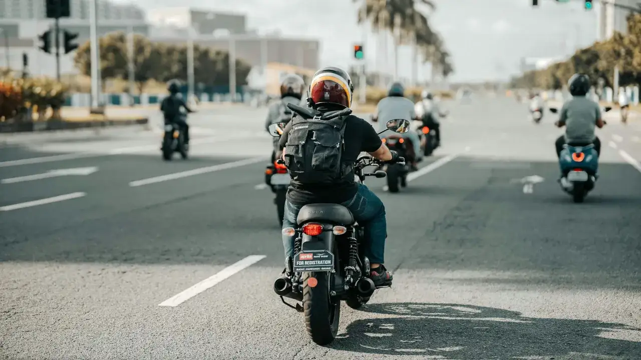 Grupa motocyklist&oacute;w jedzie drogą. Idealna pogoda dla motocyklist&oacute;w, słońce świeci, a oni cieszą się jazdą.