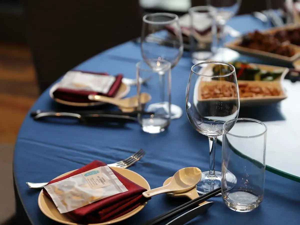 Un bel emplacement pour un verre à eau, avec des couverts et des serviettes rouges sur une table bleue.