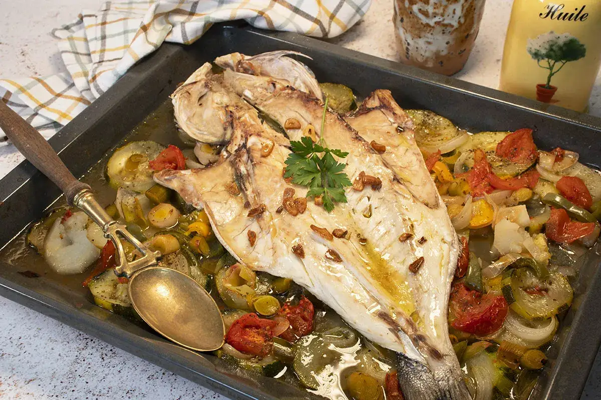 Lubina salvaje horneada con verduras, ajo y perejil, lista para servir.
