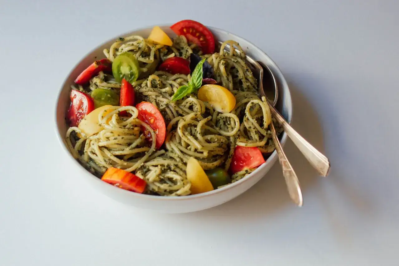 En sk&aring;l med spaghetti med pesto, toppad med f&auml;rgglada tomater och en basilika. Perfekt f&ouml;r en snabb och god pasta pesto-middag.