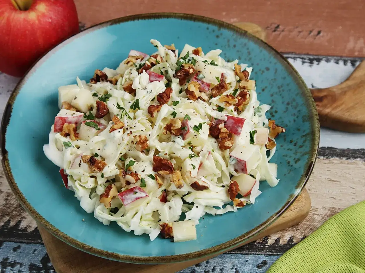 Ein frischer Spitzkohl Salat mit Apfelstücken und Walnüssen, cremiges Dressing, garniert mit Petersilie.