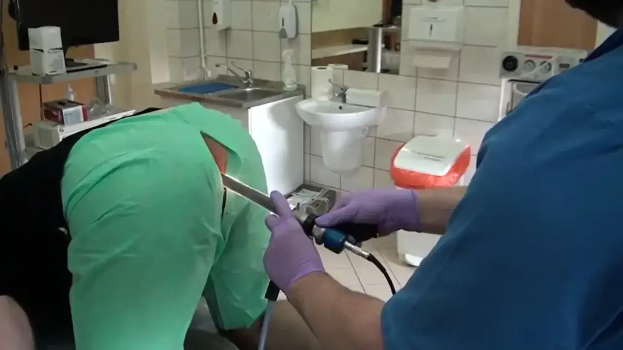 Lekarz wykonuje anoskopię, używając anoskopu do badania.