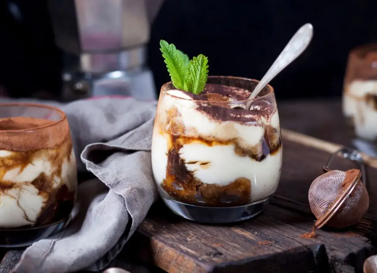 Pyszne tiramisu w pucharkach, udekorowane miętą i posypane kakao. Idealne na deser po kawie z moki.