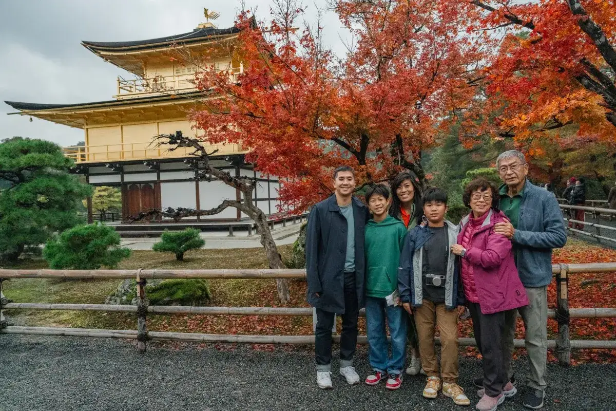 En familj njuter av höstens färger vid Kinkaku-ji, Gyllene paviljongen, en höjdpunkt på deras reseguide Japan.