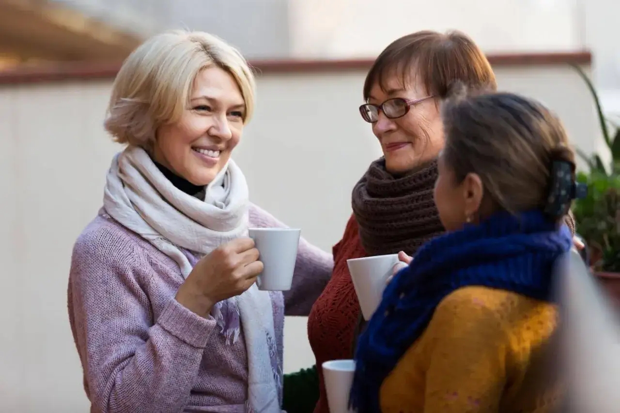Drei Frauen genießen bei einer Tasse Kaffee ein Gespräch. Solche Momente helfen, das mental health verbessern.