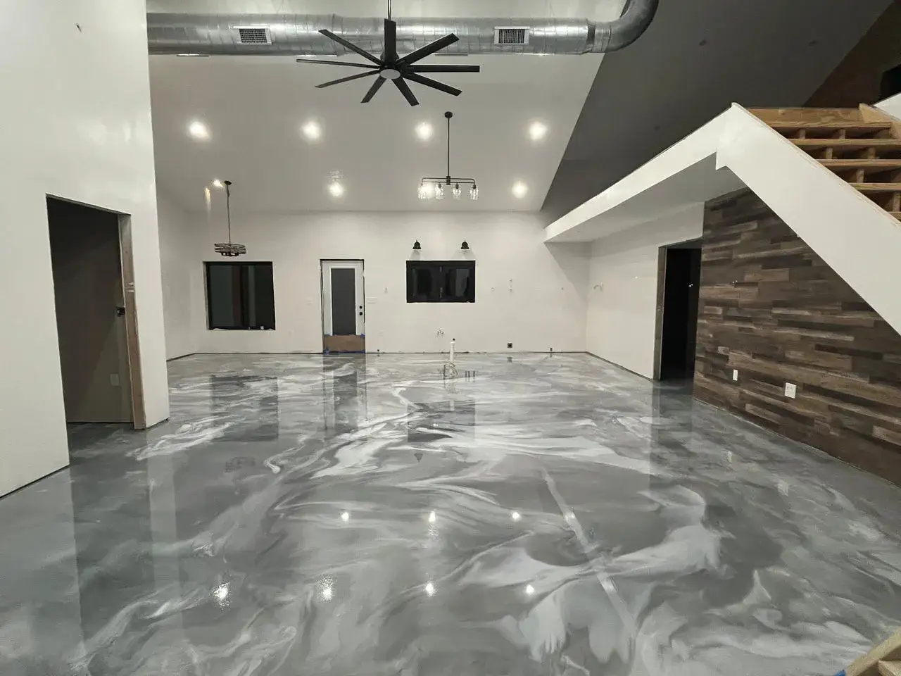 Un moderno pavimento in resina per casa, con un effetto marmorizzato grigio e bianco che riflette la luce, creando un ambiente luminoso e spazioso.