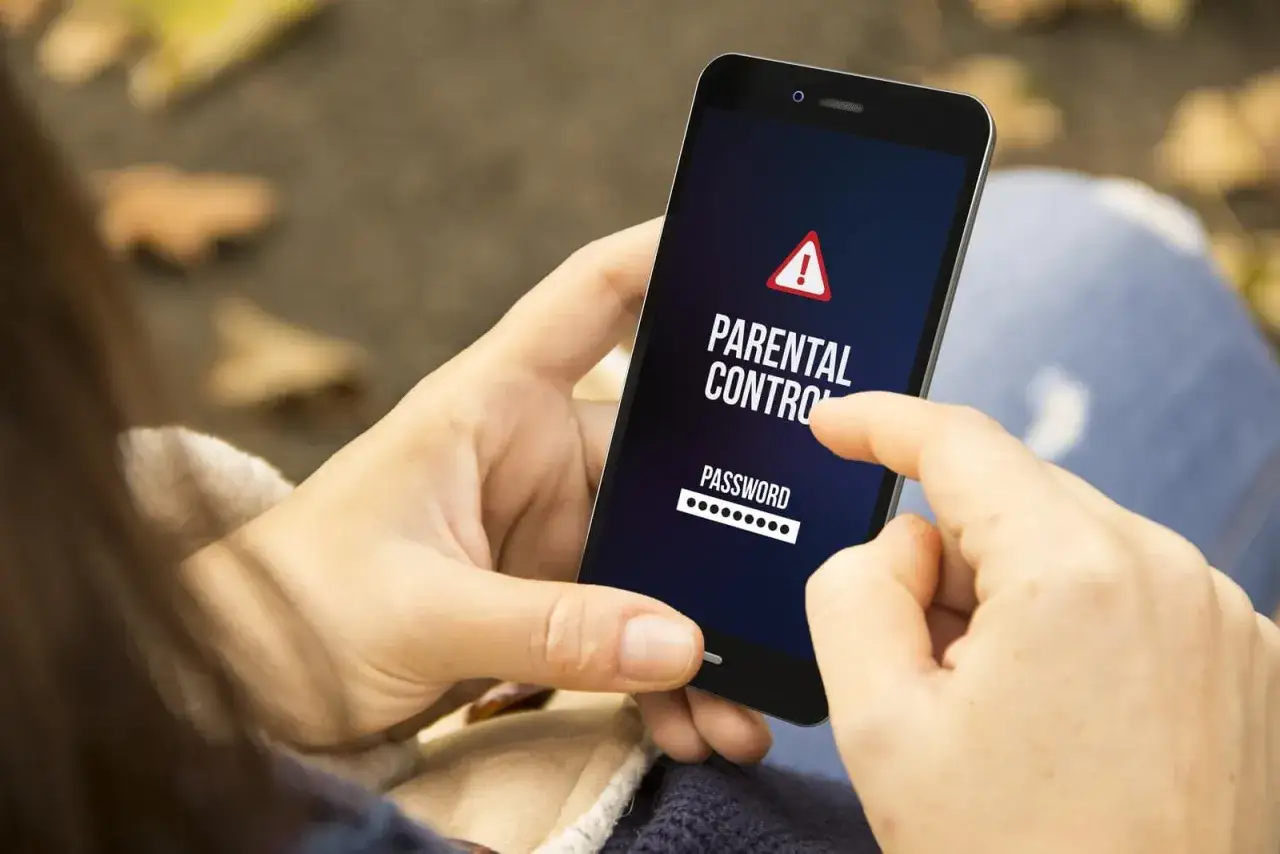 Dłoń wpisuje hasło na ekranie telefonu, aktywując kontrolę rodzicielską.