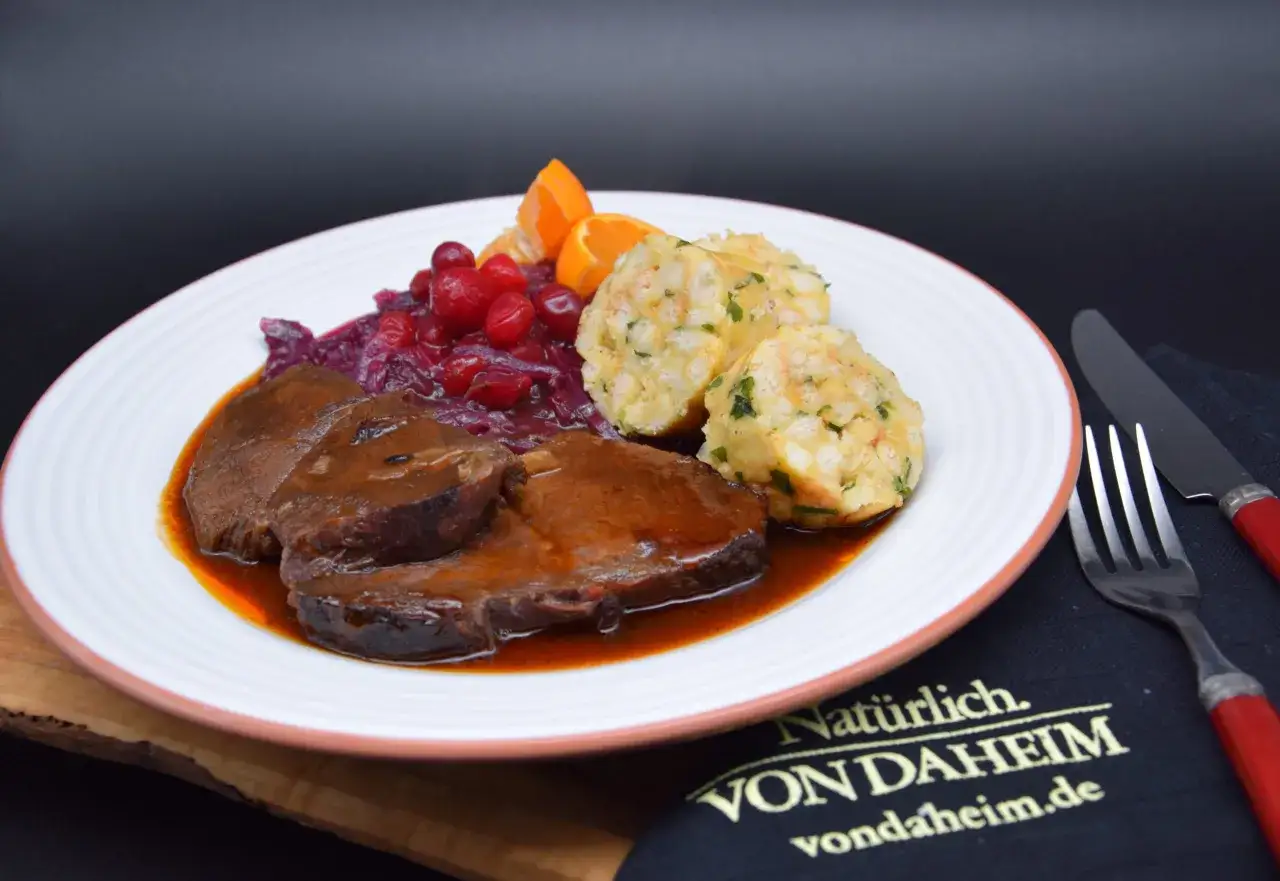 Sauerbraten selbst einlegen mit Rotwein: Zarte Fleischscheiben in dunkler Sauce, dazu Kl&ouml;&szlig;e, Rotkohl mit Cranberries und Orangenspalten.