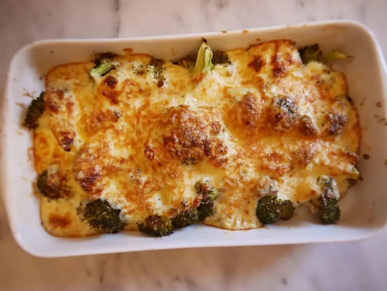 Un d&eacute;licieux gratin de brocolis tout juste sorti du four, avec une cro&ucirc;te de fromage dor&eacute;e et fondante. Un plat r&eacute;confortant et savoureux.