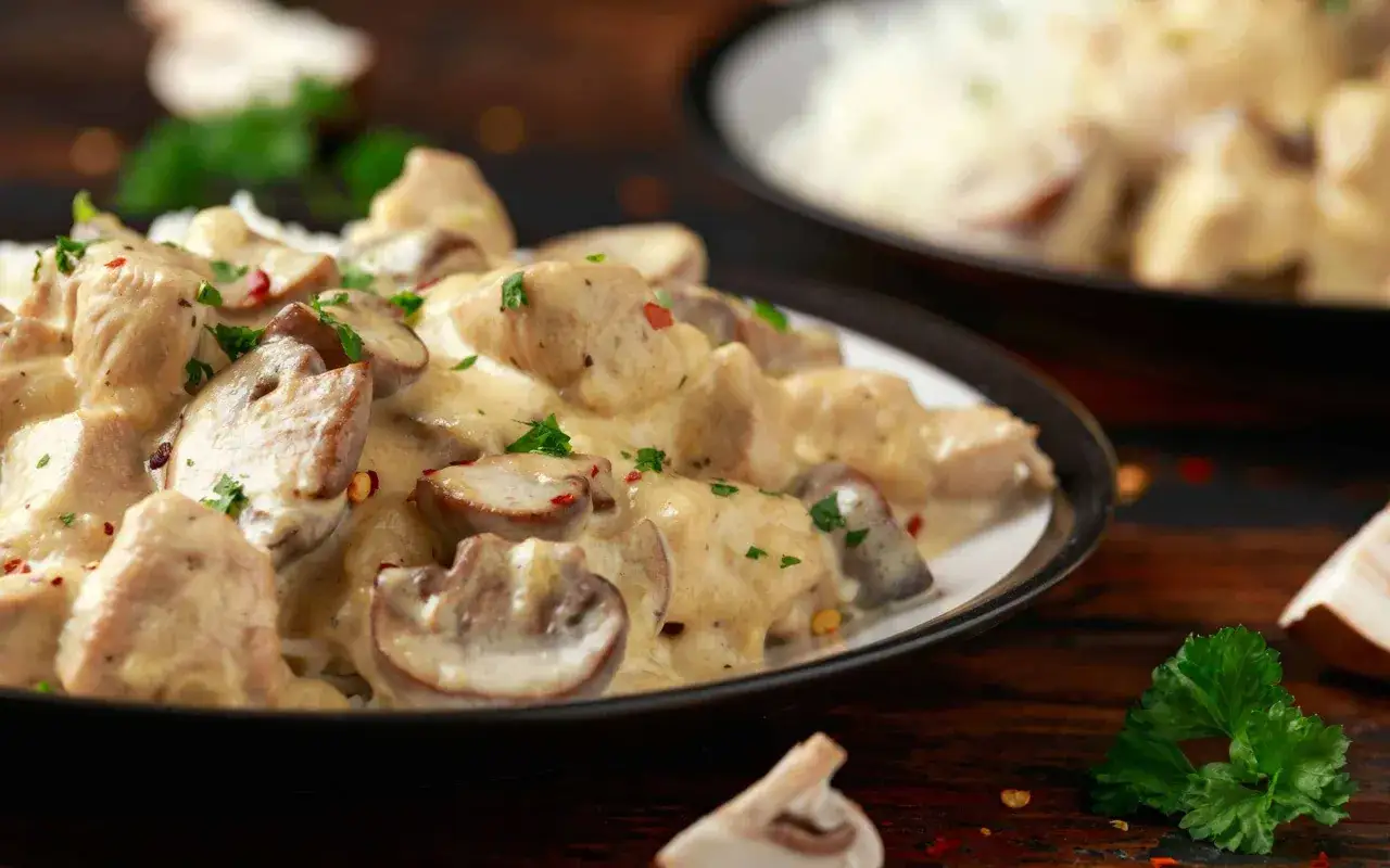 Filet de poulet crémeux aux champignons, une recette simple et savoureuse, garnie de persil frais et de flocons de piment.