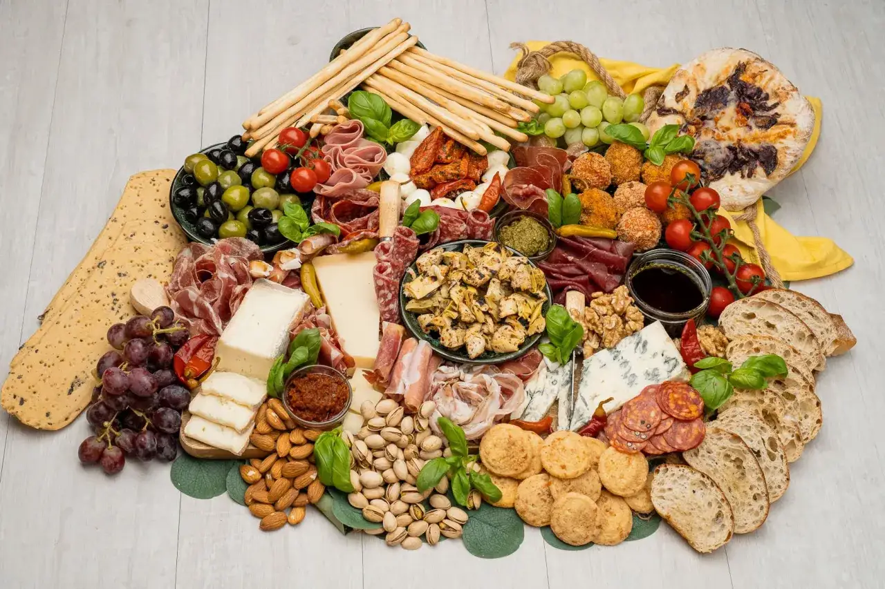 Bogata deska ser&oacute;w i wędlin: oliwki, winogrona, grissini, sery, salami, orzechy, pieczywo. Idealna na spotkanie, by spr&oacute;bować, co to crudo.