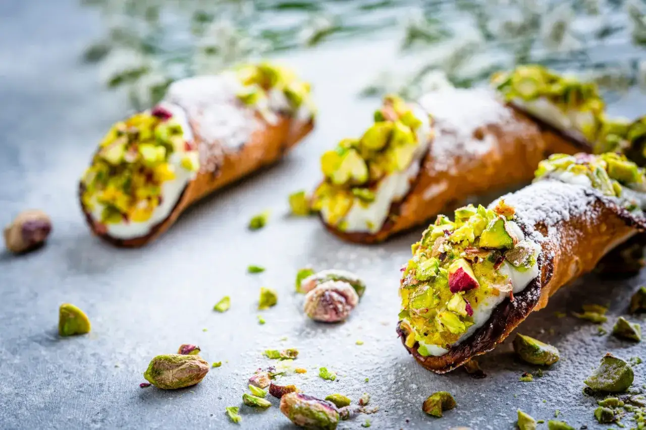 Pyszne cannoli pistacjowe posypane cukrem pudrem i orzechami. Idealna przekąska dla łasuchów.
