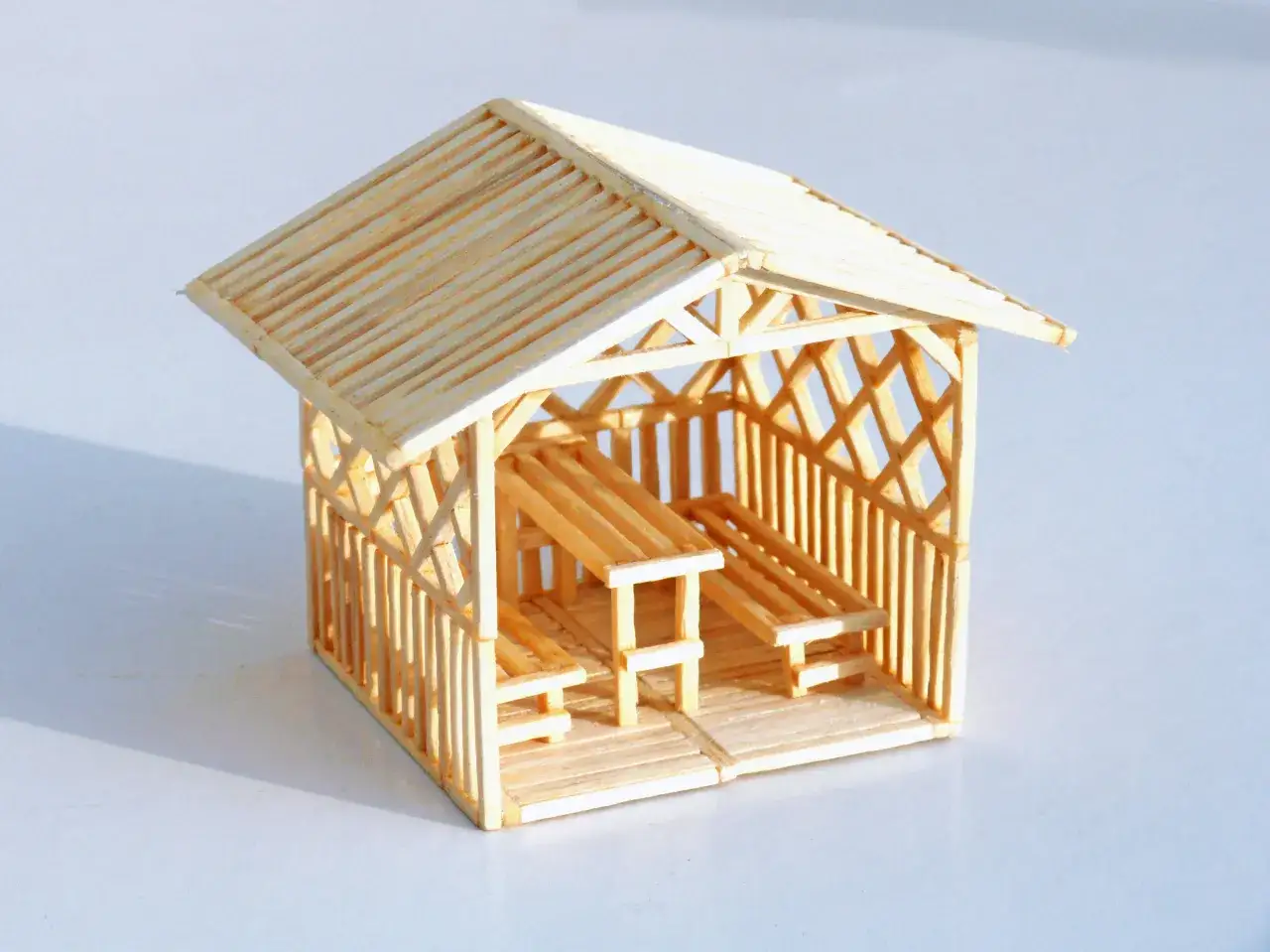 Miniaturowy domek z zapałek z ławkami i stołem. Inspiracja, jak zrobić domek z zapałek.