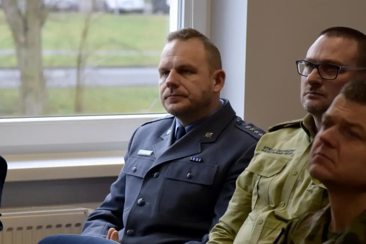 Mężczyźni w mundurach, jeden w granatowym, drugi w zielonym z napisem 