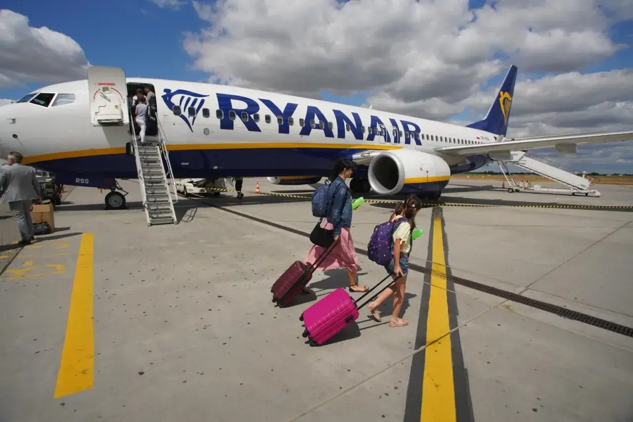 Rodzina z walizkami idzie do samolotu Ryanair, gotowa na loty na Sardynię.