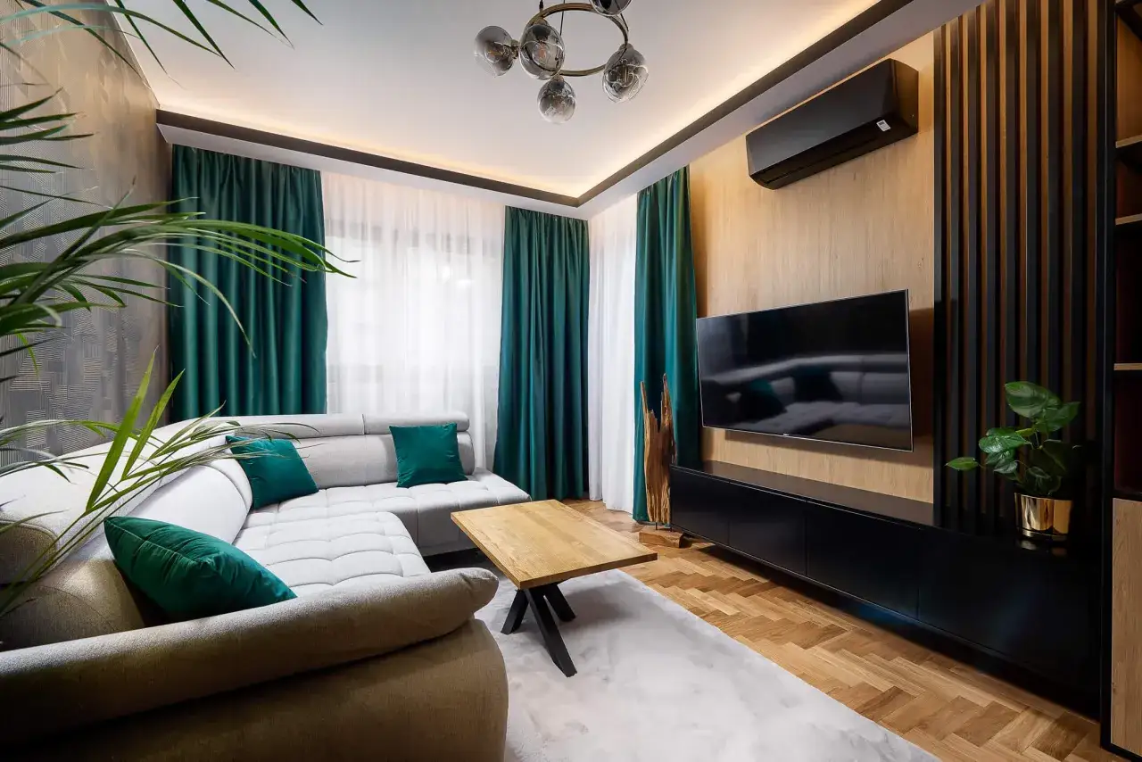Nowoczesny salon w stylu eklektycznym: szara kanapa, drewniany stolik, turkusowe zasłony i designerska lampa tworzą przytulną przestrzeń.