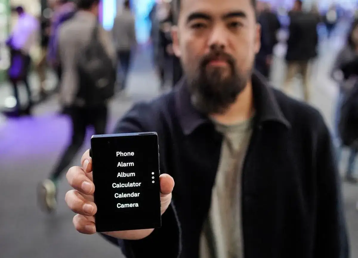 Un homme tient un t&eacute;l&eacute;phone minimaliste affichant 