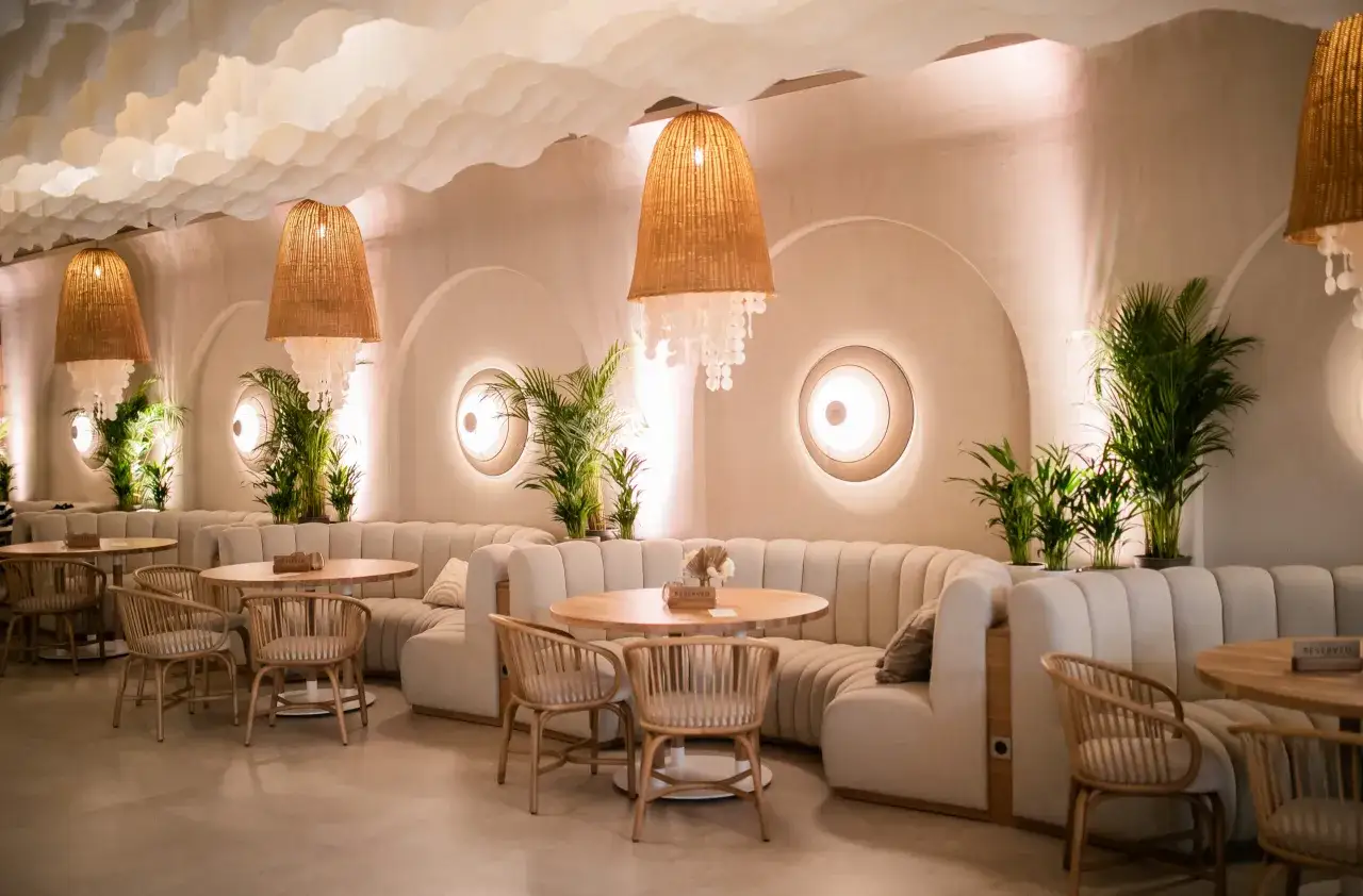 Przytulne wnętrze restauracji w Gdańsku z miękkimi kanapami, drewnianymi stołami i plecionymi lampami.