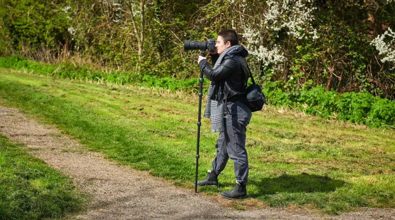 Osoba z aparatem fotograficznym opiera się o monopody, by uchwycić piękno przyrody.