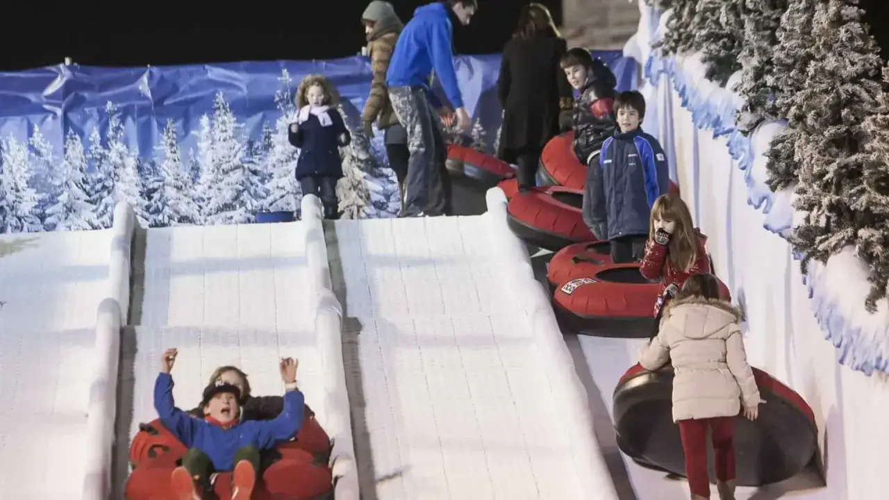 Niños disfrutan de trineos en la Plaza del Pilar, deslizando por pistas nevadas en tubos inflables.