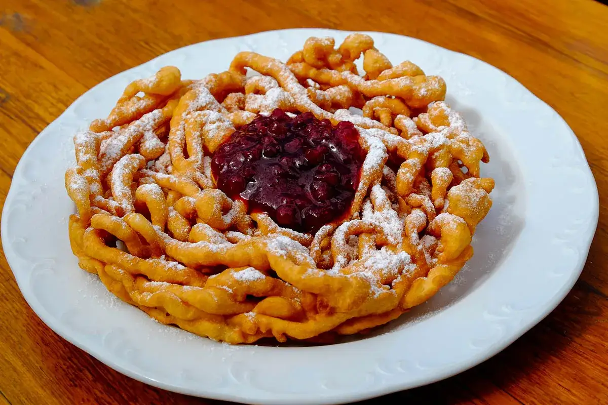 Strauben dorati e croccanti, spolverati di zucchero a velo e guarniti con confettura di frutti di bosco. Una deliziosa ricetta da provare!