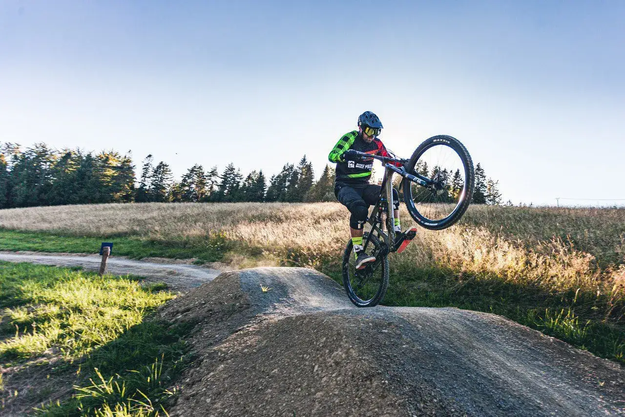 Rowerzysta wykonuje wheelie na trasie jednego z najlepszych bike parków w Polsce.