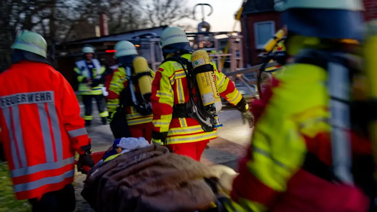 Feuerwehrleute im Einsatz nach einem Brand in einem alten Heim. Sie tragen Schutzkleidung und Atemschutzger&auml;te.