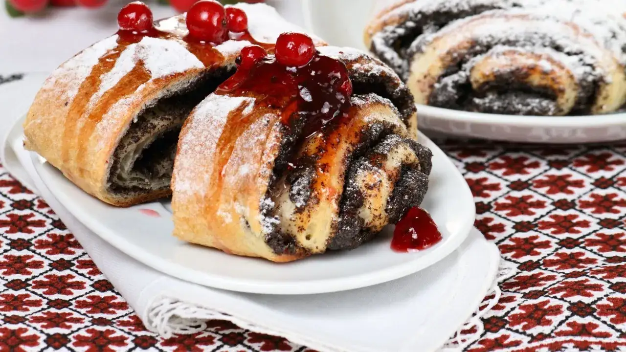 Zwei Mohnschnecken, bestäubt mit Puderzucker und garniert mit Kirschen. Ein süßer Genuss, der an die Schwangerschaft erinnert.