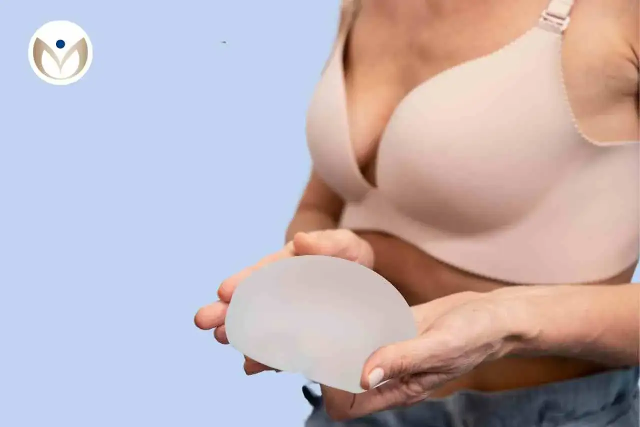Kobieta trzyma implant piersi. Zastanawiasz się nad operacją biustu? Cena zabiegu może być różna.