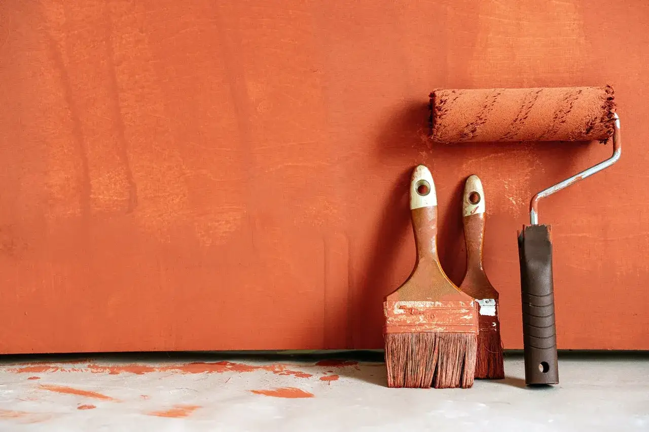Pinceaux et rouleau de peinture orange sur fond textur&eacute;. Id&eacute;al pour savoir comment rattraper une peinture mal faite.