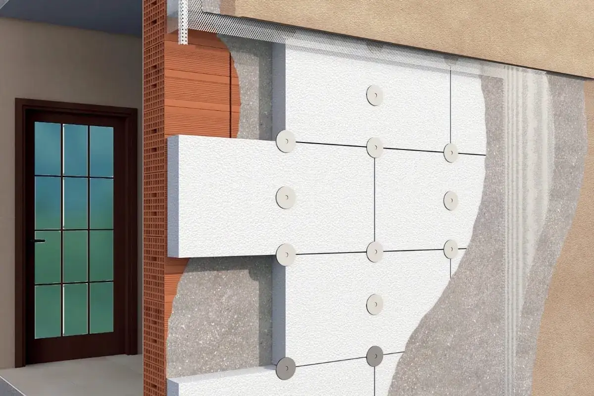 Dettaglio costruttivo di un cappotto casa: pannelli isolanti in polistirene fissati a una parete in laterizio, con intonaco e rete di armatura.