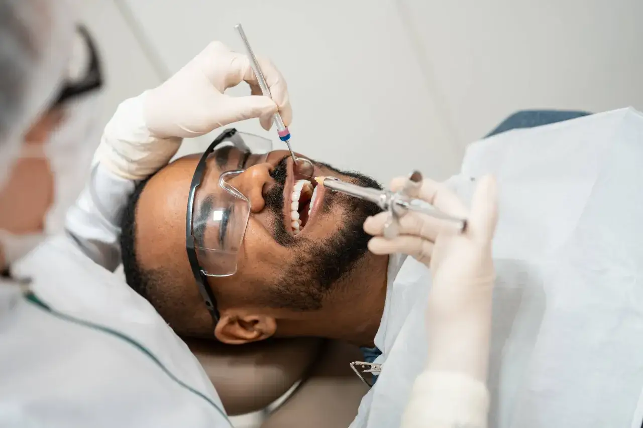 Dentysta podaje znieczulenie, przygotowując pacjenta na zabieg. To ważny etap, by zapewnić komfort podczas zakładania opatrunku na zęba.