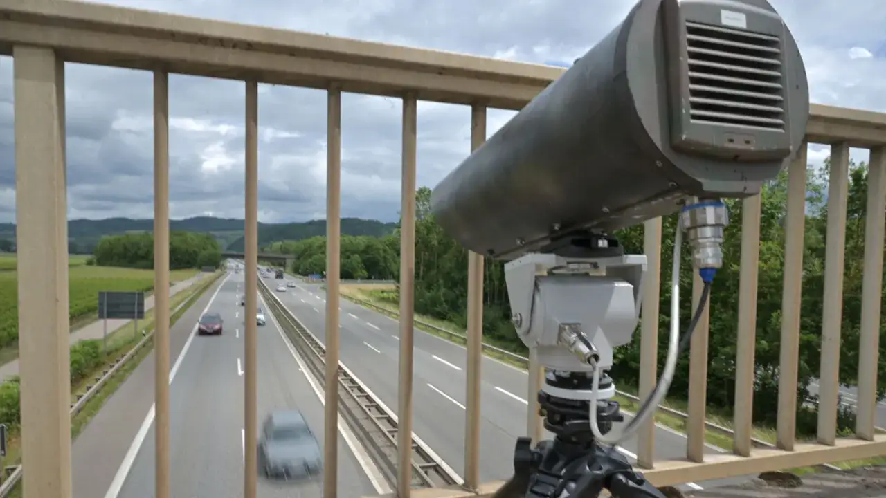 Monocam-Blitzer überwacht die Autobahn. Ein graues Gerät auf einem Stativ blickt auf die vorbeifahrenden Autos.