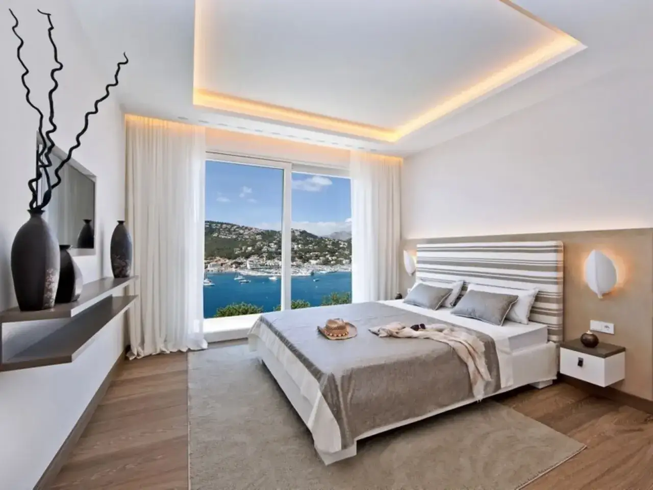 Camera da letto con moderno controsoffitto illuminato, letto king-size e vista mare mozzafiato.