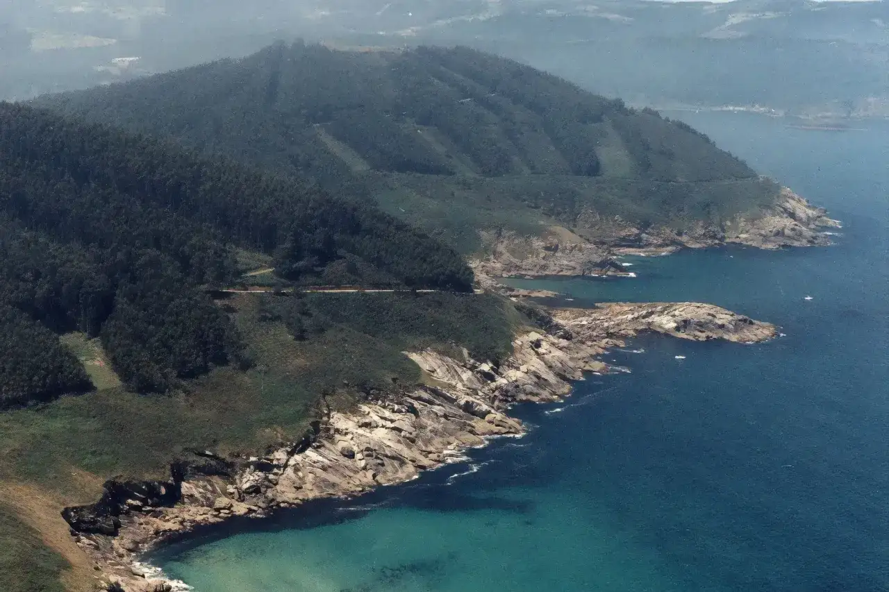 Costa rocosa y verde con el mar azul turquesa. Se vislumbra la playa Portonovo Viveiro, un rincón gallego de ensueño.