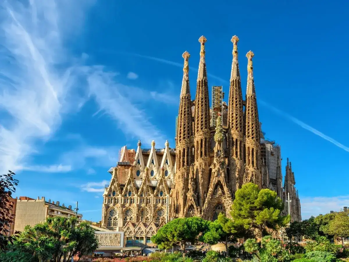 La Sagrada Familia, avec ses tours imposantes sous un ciel bleu, témoigne des travaux continus. Un chef-d'œuvre architectural en constante évolution.