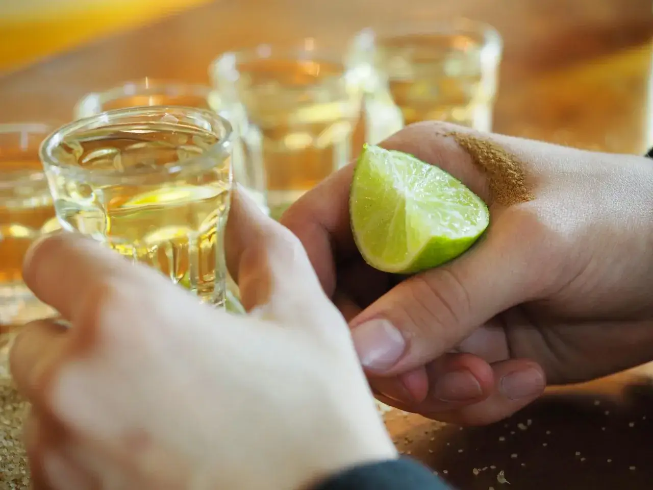 Hände bereiten Tequila-Shots vor, mit Limette und Salz. Die Tequila-Reihenfolge wird hier perfektioniert.