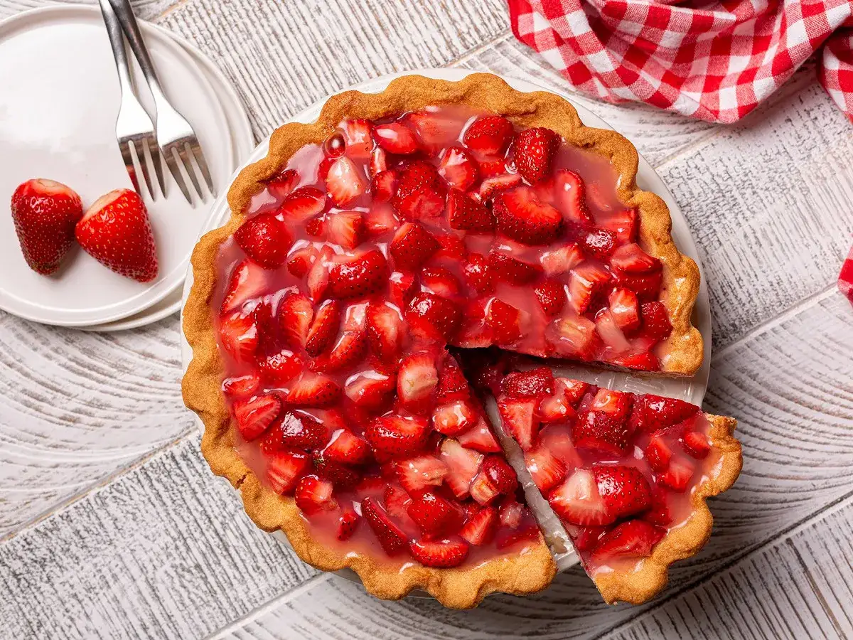 Une d&eacute;licieuse tarte aux fraises de grand-m&egrave;re, garnie de fruits frais et napp&eacute;e d'une gel&eacute;e brillante. Une part a &eacute;t&eacute; coup&eacute;e, pr&ecirc;te &agrave; &ecirc;tre d&eacute;gust&eacute;e.